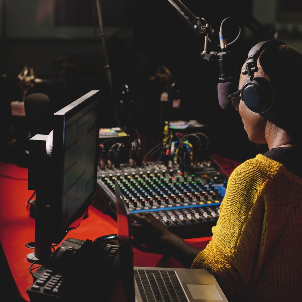 Black radio host in headphones working in dark studio Black radio host in headphones working in dark studio