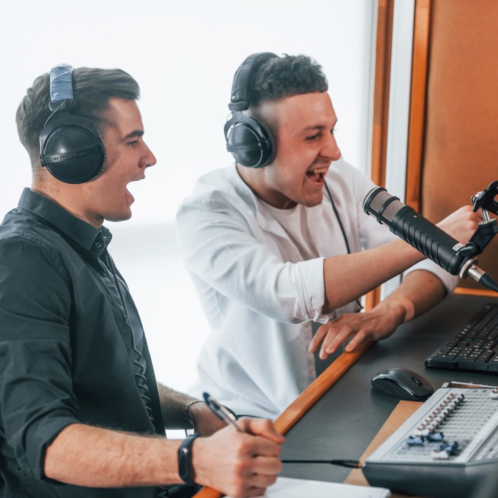 Two guys is indoors in the radio studio is busy by broadcast Two guys is indoors in the radio studio is busy by broadcast